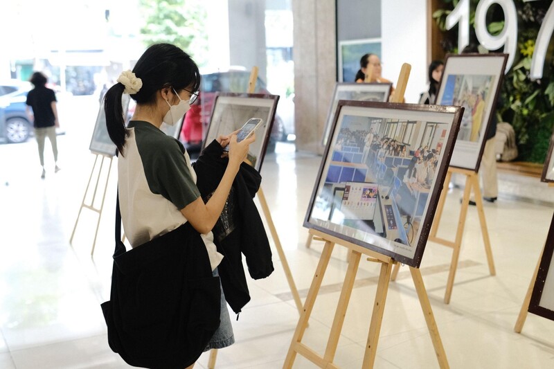 A person looking at a picture on a standDescription automatically generated